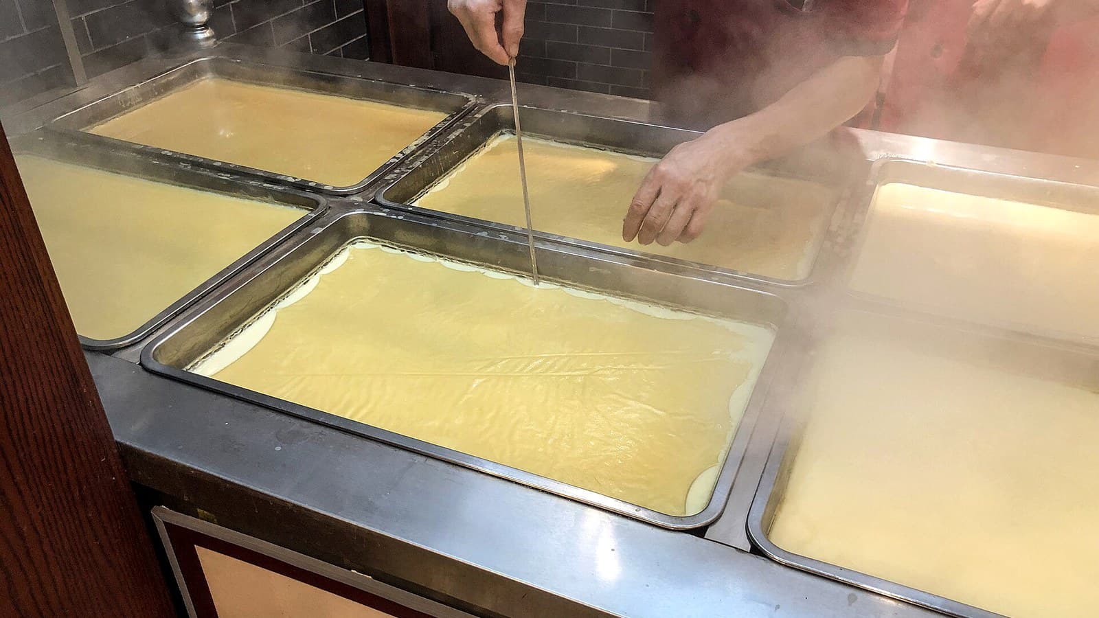 Fresh tofu skin setting on heated trays during bean-based production