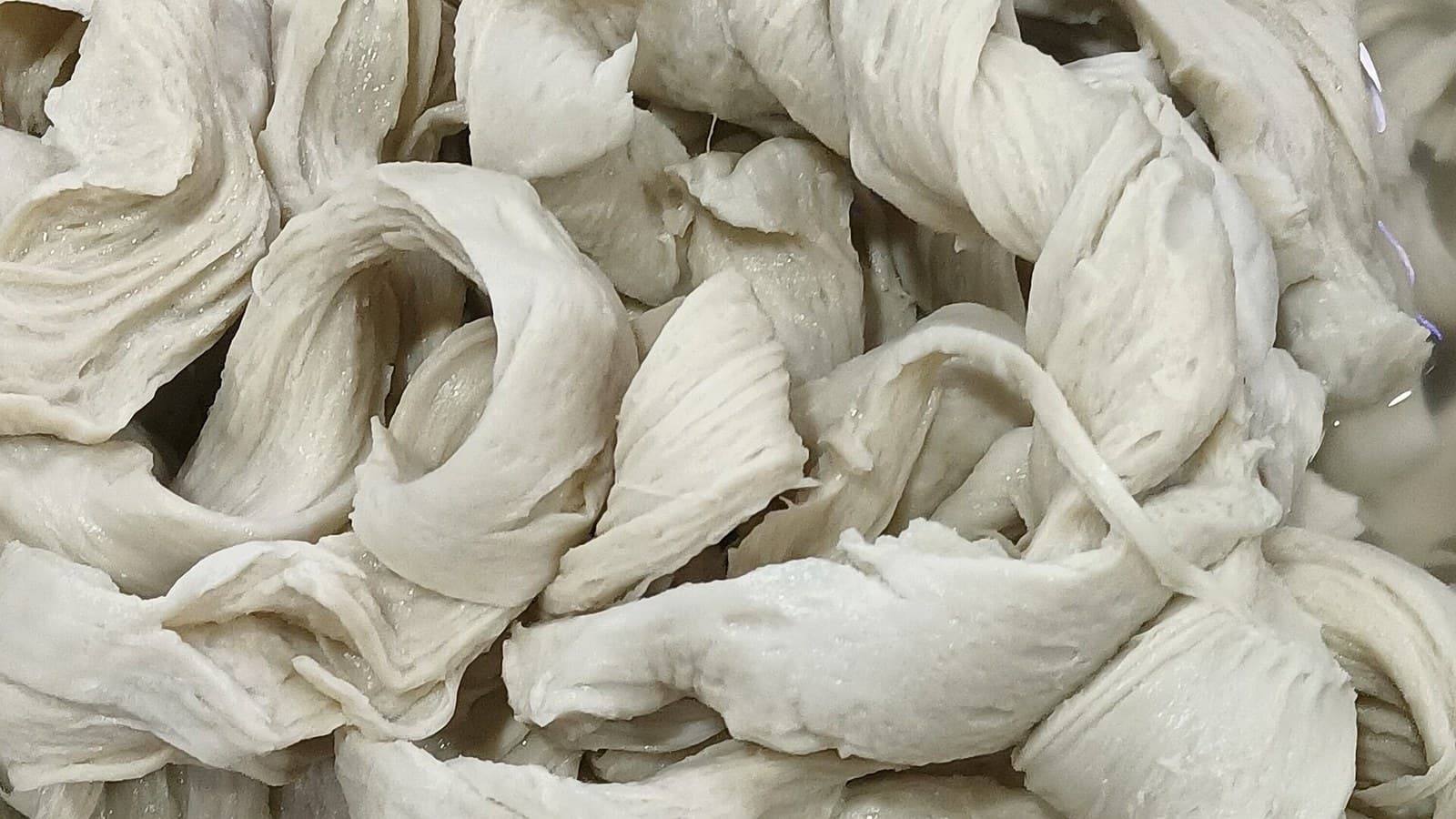 Tofu skin sheets spread in a production vat to show soy-sheet texture