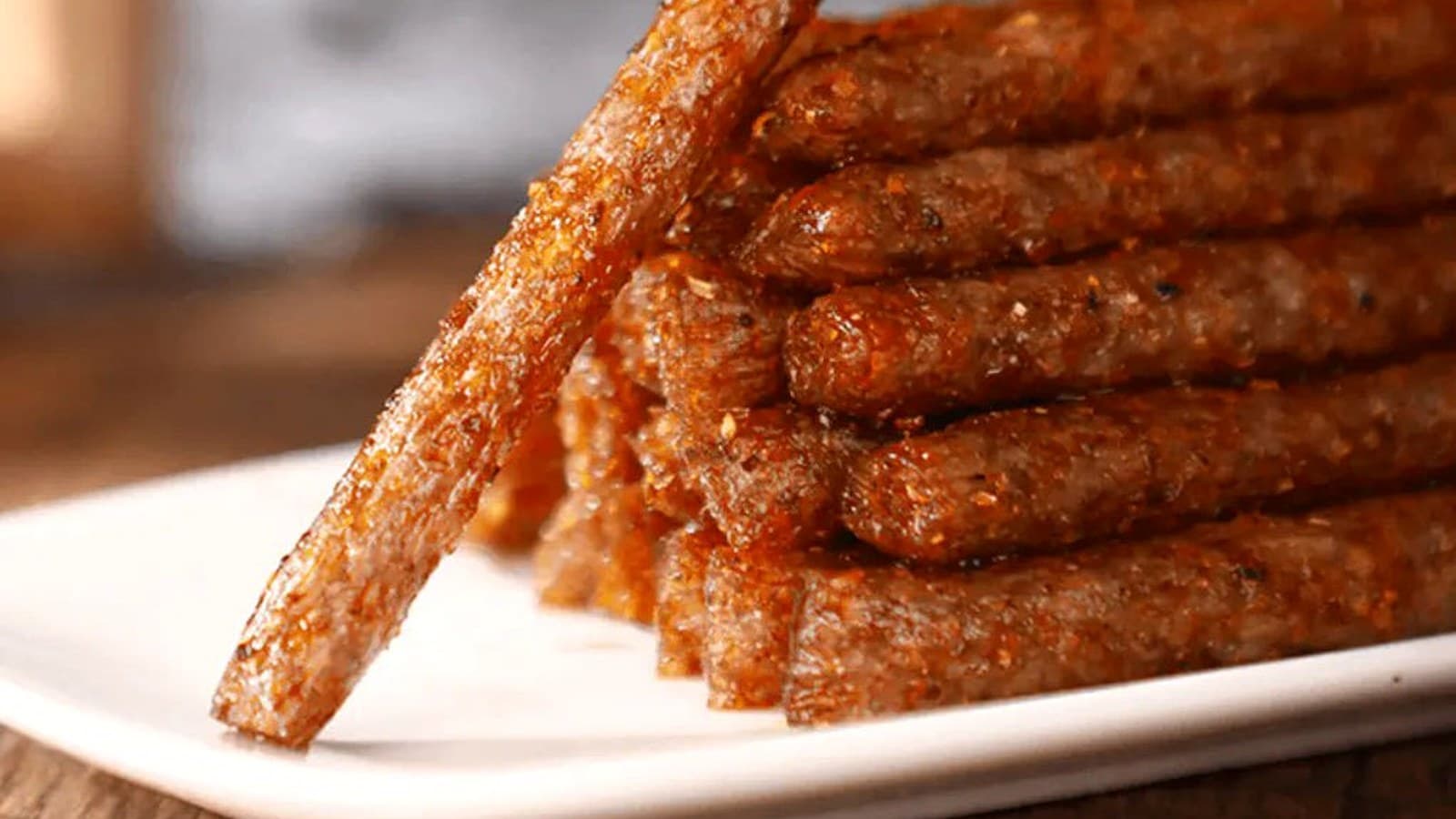 Ridged latiao pieces with glossy chili oil and sesame seeds in close view