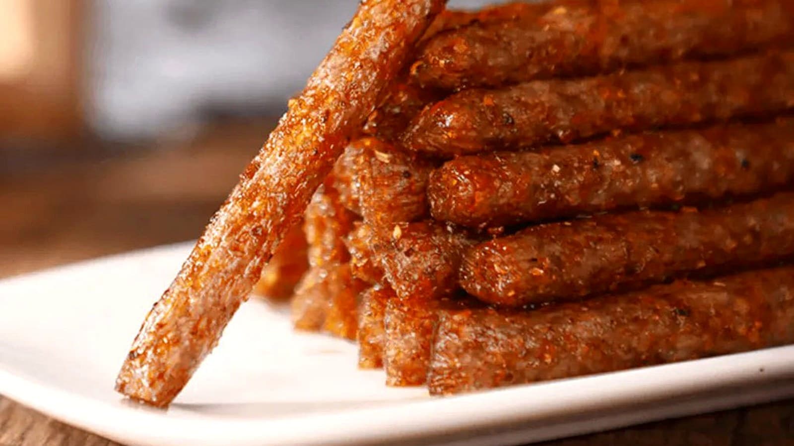 Ridged latiao pieces with glossy chili oil and sesame seeds in close view