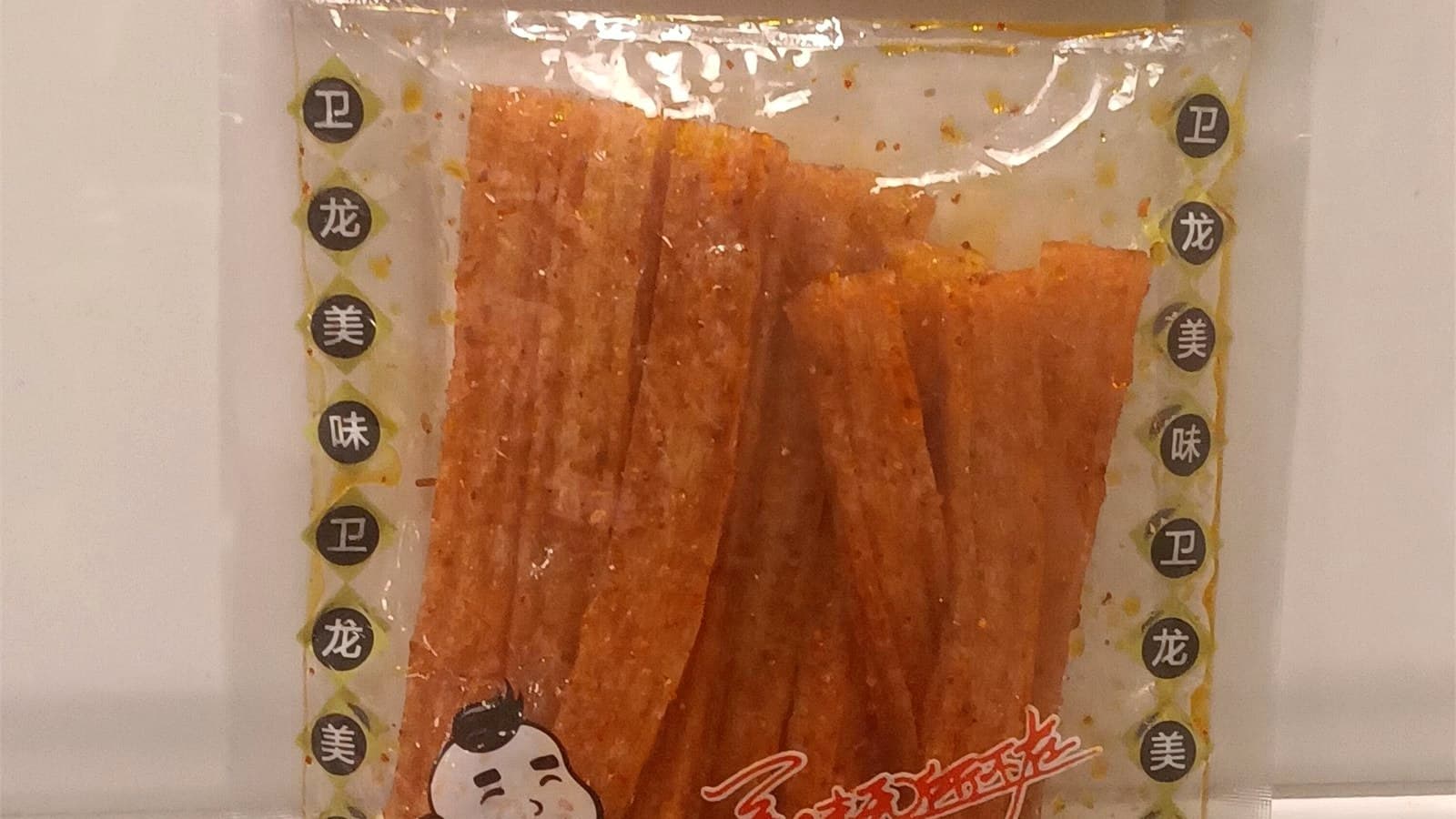A sealed Weilong spicy gluten package standing beside the opened product strips